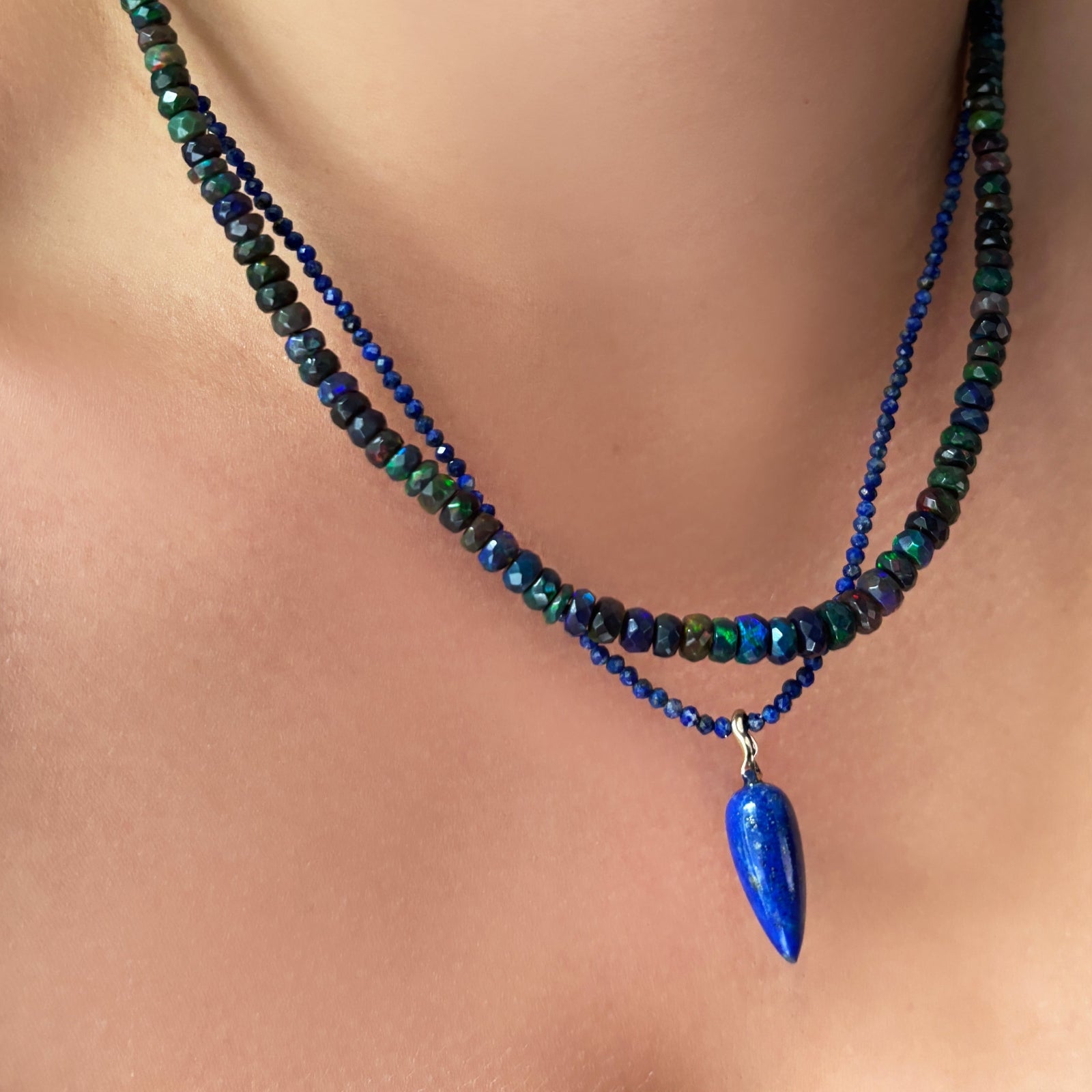 night sky faceted opal necklace layered with lapis slim gemstone necklace with lapis drop charm on the neck.
