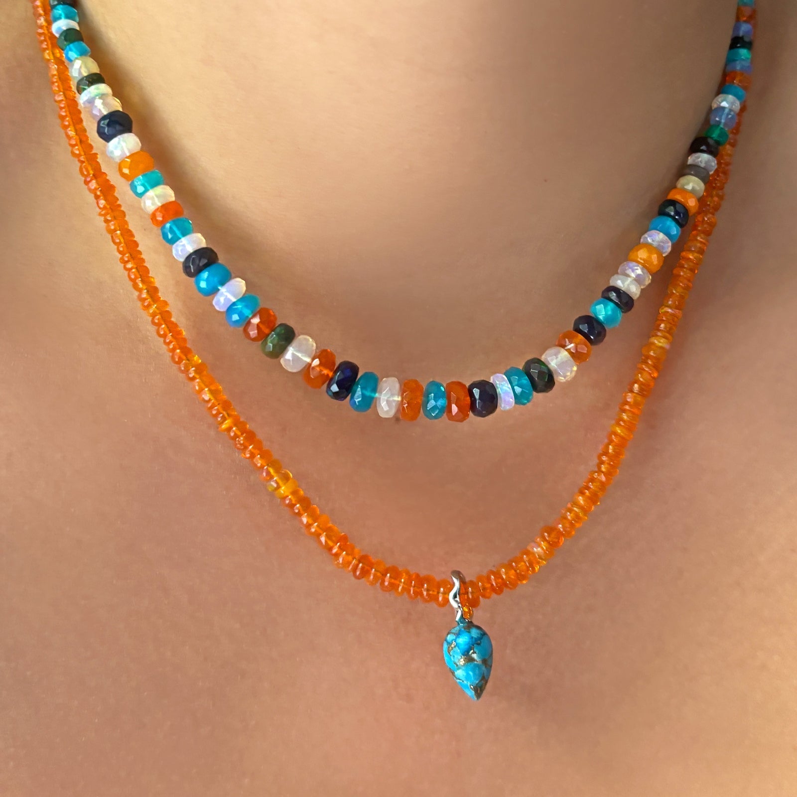orange opal necklace with turquoise drop charm layered with jaipur jazz faceted opal necklace on the body.