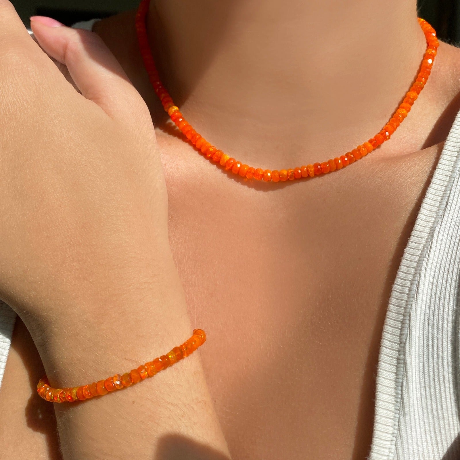 Shimmering beaded necklace made of faceted opals in shades of orange on a gold linking ovals clasp.