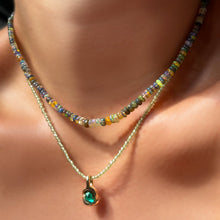 Tide Pool Opal Necklace layered over a peridot slim gemstone necklace with molten knot charm with emerald on the neck.