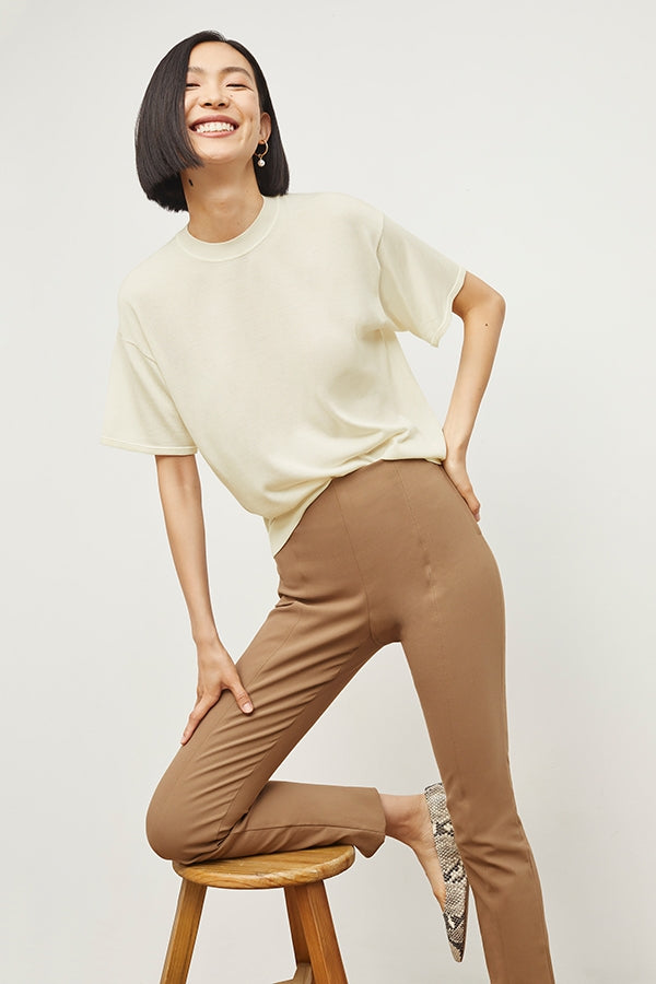 Front image of a woman sitting wearing the Foster Pant—Everstretch in Saddle | Grid | Exclude